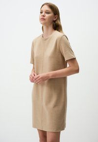 Beiges Kurzarmkleid aus weichem Stoff. Es verfügt über einen runden Ausschnitt und einen geraden Schnitt mit subtilen Nahtdetails auf der Vorder- und Rückseite.