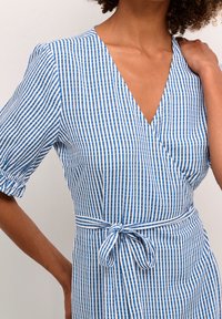 Vestido envolvente a rayas azul y blanco con mangas cortas abullonadas, un escote en V profundo y una cintura atada para un ajuste regulable. Tela de algodón, textura ligera.