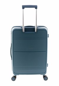 Maleta rígida en azul profundo, con una superficie texturizada, asa retráctil y cuatro ruedas para facilitar la maniobrabilidad.