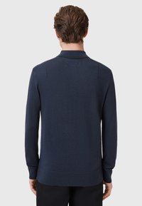 Marineblauwe poloshirt met lange mouwen, gemaakt van een zachte gebreide stof; beschikt over een geribbelde kraag, manchetten en zoom; minimalistisch ontwerp met subtiele stikdetails.