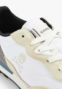 Weiße Sneaker mit Akzenten aus Wildleder in Beige und Grau. Verfügt über ein Totenkopf-Logo, schwarzes Innenfutter und weiße Schnürsenkel. Gummisohle mit blauen Details.