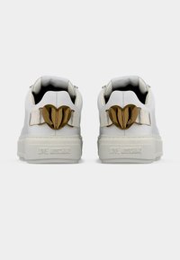 Λευκά sneakers με πλατφόρμα, με διακοσμητικά σε σχήμα χρυσής καρδιάς και την επωνυμία "Love Moschino" στη φτέρνα.