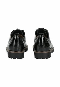 Paio di scarpe in pelle lucida nera con suole spesse e scanalate, viste da dietro su uno sfondo bianco.