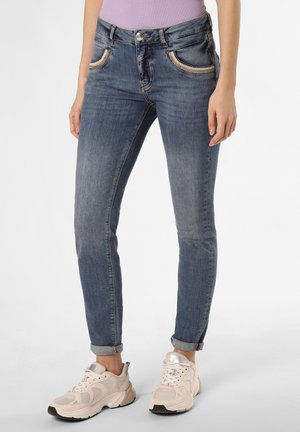Skinny-fit blue denim jeans with faded texture, contrasting stitching, and rolled cuffs, paired with light-colored athletic shoes.