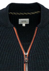 Veste zippée côtelée bleu marine avec des touches de fermeture éclair orange, col tricoté et couture intérieure en croix jaune. L'étiquette indique "camel active", taille M.