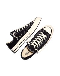 Pereche de adidași Converse joși, alb-negru, cu șireturi albe, capete de cauciuc la vârfuri și logo-ul vizibil al mărcii în interiorul uneia dintre pantofi.