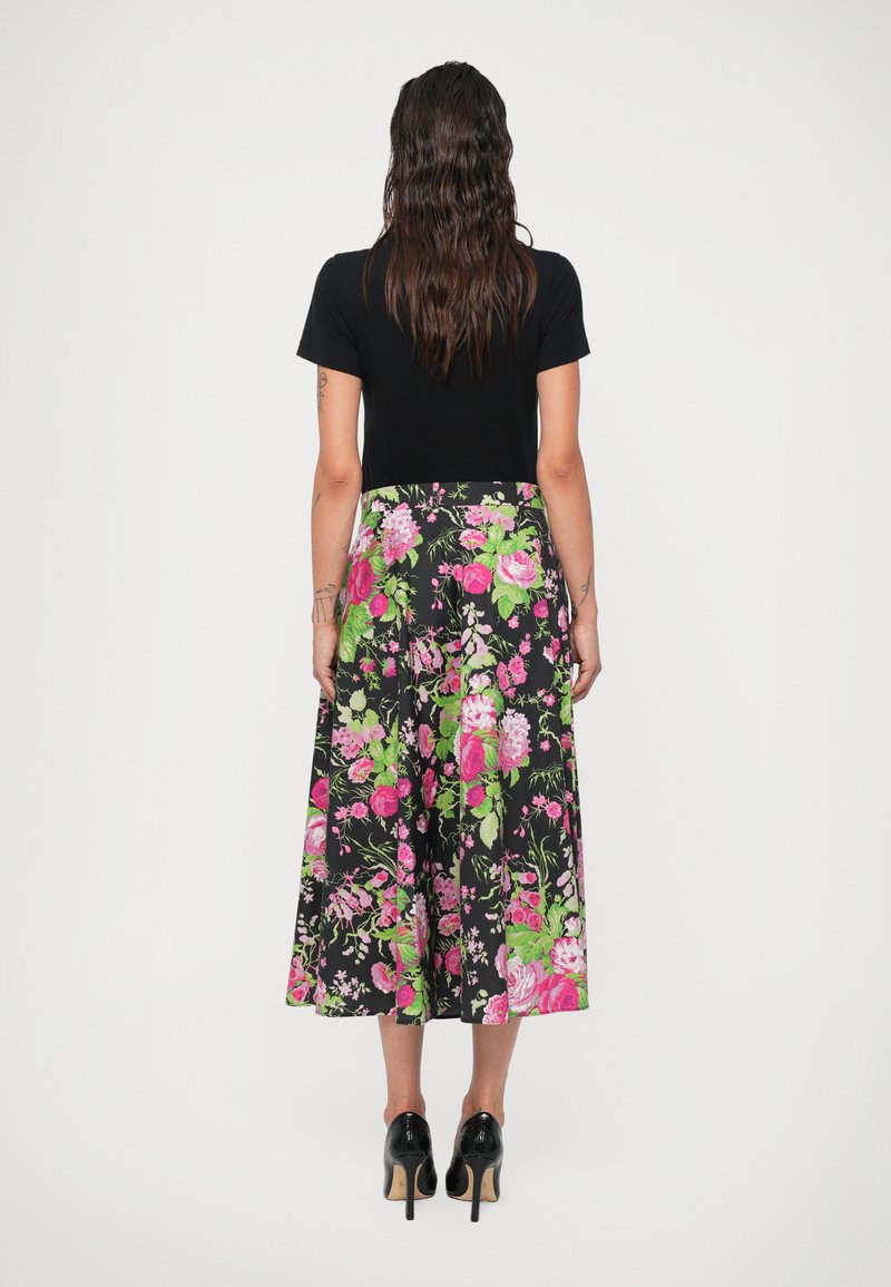 Sort t-shirt over en lang, blomsterprintet nederdel med sort baggrund og rosa samt grønne blomster. Materialet ser blødt ud med en glat tekstur.