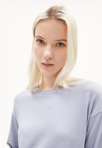 Helllila gestrickter Pullover mit Rundhalsausschnitt und kurzen Ärmeln, der eine glatte Textur und einen lässigen Schnitt aufweist.