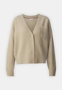 Beige stickad cardigan med v-ringning, fem knappar, ribbad textur och en bröstficka med subtil logobroderi. Kort passform.