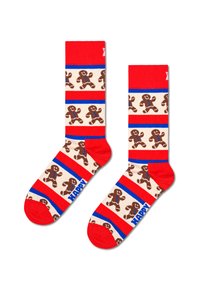 Czerwone skarpetki w paski, z wzorem ciastek piernikowych i niebieskimi akcentami, z wyrazem "SZCZĘŚLIWY" w wyraźnym napisie na kostce.