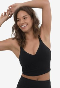 Top corto sportivo nero con scollatura a V, realizzato in tessuto morbido, presenta spalline larghe e una silhouette aderente.