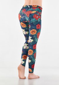 Leggings floreali con uno sfondo blu scuro, che presentano fiori vibranti rossi, gialli e bianchi, insieme a motivi di foglie verdi. Tessuto elasticizzato, design aderente.