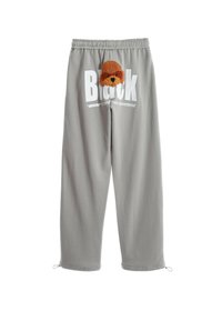 Pantalones de chándal grises con cinturilla elástica, que presentan un gran texto en blanco y un aplique de perro marrón texturizado en la parte frontal. Cuerdas ajustables en los tobillos.