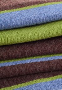 Couvertures en laine avec des rayures bordeaux, vert et bleu ; texture douce avec un motif tricoté ; empilées et se chevauchant légèrement.