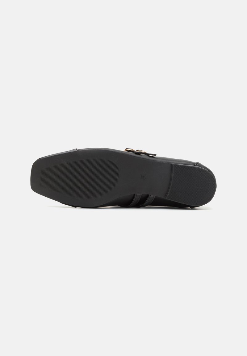 Schwarze Schuhsohle aus strukturiertem Gummi für Grip, mit einem glatten Obermaterial und dekorativen Schnallenakzenten an der Seite.