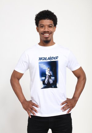 Hvid bomulds T-shirt med et grafisk design af en mand, der holder et sværd, med ordet "HIGHLANDER" i blåt over billedet.