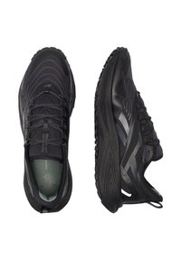 Čierne športové topánky s textúrovaným syntetickým zvrškom s vlnovými vzormi, reflexnými akcentmi a gumovou podrážkou pre trakciu.