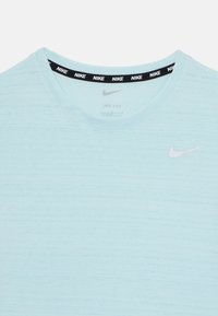 Světle modré tričko Nike Dri-FIT s šedým logem na hrudi a černým páskovaným výstřihem se opakujícím bílým brandingem Nike. Hladká textura.