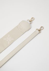 Beige strap with textured leather and fabric sections, featuring gold hardware and embossed floral design; adjustable length for versatility.