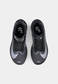 Des chaussures de course noires avec un dessus texturé, des accents gris et des lacets noirs. Présente un logo swoosh distinctif sur les côtés.