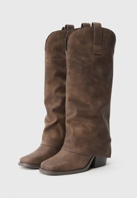 Braune Stiefel aus Kunstleder in knielanger Höhe mit einem strukturierten Schaft, leicht schlaffem Design, spitzem Fuß und niedrigem Blockabsatz.