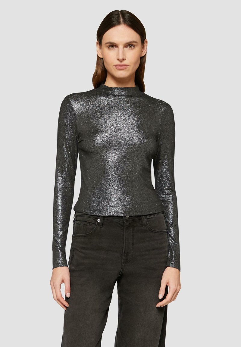 Schwarzes, glänzendes Langarm-Oberteil mit hohem Kragen, aus glitzerndem Material, kombiniert mit dunklen, geraden Jeans.