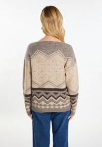 Pulover tricotat bej cu modele geometrice în nuanțe de marron și gri. Dispune de un gât larg și o croială lejeră. Materialul este moale și texturat.