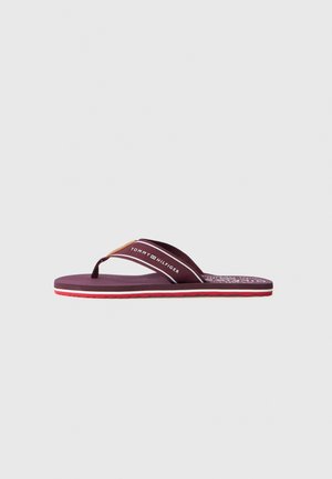 Burgunder flip-flop med gummisåle, som har en teksturert fotseng, kontrastfarget rød såle og en merket tekstilstropp.