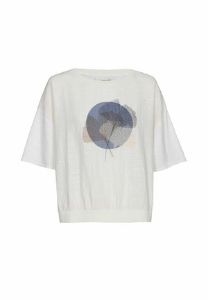 Witte blouse met korte mouwen en losse pasvorm, met een centrale blauwe cirkel en overlappende delicate bladillustraties in blauwe en beige tinten.