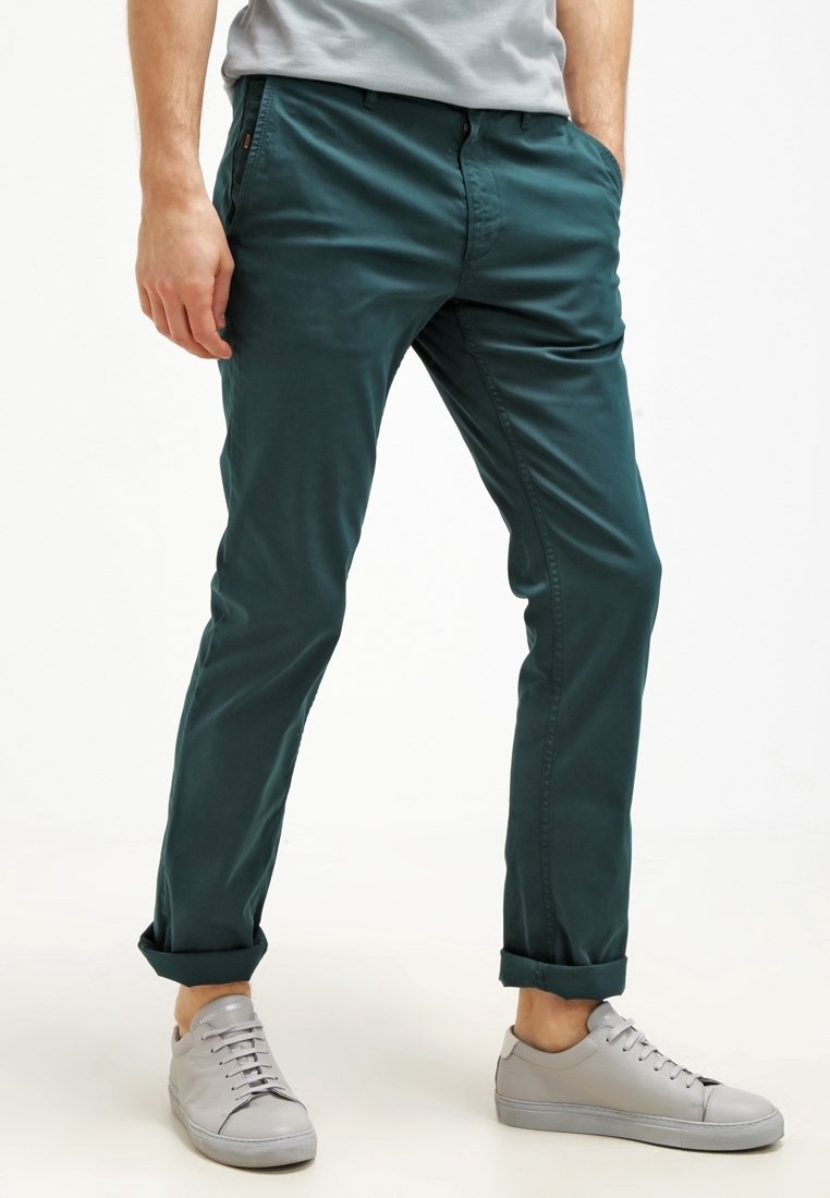 Teal färgade bomullschinos med en tapered fit, som har framfickor, bälteöglor och uppvikta fållar, tillsammans med ljusgrå sneakers.