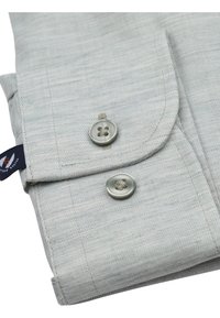 Lichtgrijze shirtstof met een subtiele gestreepte textuur. Heeft twee ronde knopen en een omgeslagen kraag voor een nette afwerking.
