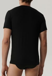 Czarna koszulka z krótkim rękawem, wykonana z gładkiego, elastycznego materiału. Dopasowany krój z okrągłym dekoltem i bez widocznych logo czy wzorów.