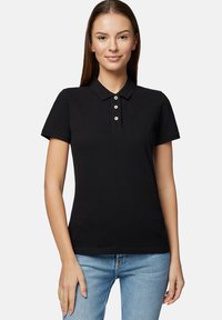 Czarna, krótko rękawowa koszulka polo wykonana z bawełny, z kołnierzykiem i zapięciem na trzy guziki. W połączeniu z jasnoniebieskimi dżinsami.