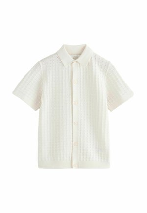 Īsām piedurknēm krekliņš krēmkrāsā ar pogām, izgatavots no adīta auduma ar teksturētu rakstu, ar apkakles izgriezumu un ribotu apakšmalu.
