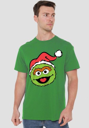 Green cotton T-shirt featuring a large, cartoonish green face with orange eyebrows and a red Santa hat, accented with a white pom-pom.