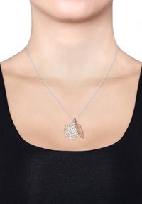Sølv kædannelse med et cirkulært vedhæng, der har et geometrisk mønster og en rosaguld fjeraccent. Tekstureret og detaljeret design.