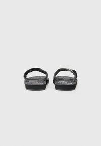 Black flip-flops with textured footbed, rubber sole, and fabric straps featuring a curved design and stitching detail.
