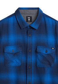 Camicia a quadri blu e navy in tessuto, con colletto a bottoni, due tasche sul petto e bottoni neri. Etichetta con logo visibile sulla tasca.