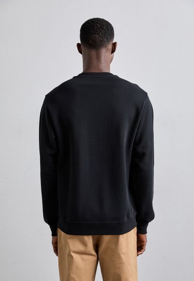 Sweatshirt noir, tissu doux, poignets et ourlet ajustés, style classique à col rond, design minimal, vue arrière avec texture unie.