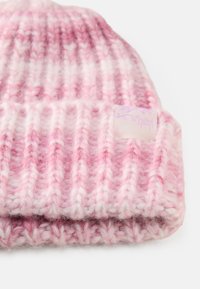 Gebreide beanie in verschillende tinten roze, met een geribbelde textuur, zacht materiaal en een klein stoffen label met paarse tekst.