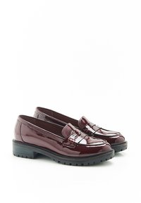 Mocasines de charol burdeos con una suela baja de goma negra, que presentan un diseño de ranura para moneda y una textura suave y brillante.