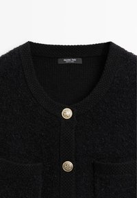 Cardigan nero con texture, collo rotondo, due bottoni decorativi dorati e tasche a toppa frontali, etichettato Massimo Dutti.