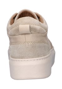 Beige suede sneakers with a smooth leather heel tab, rounded shape, padded collar, and subtle stitching details. Flat rubber sole.