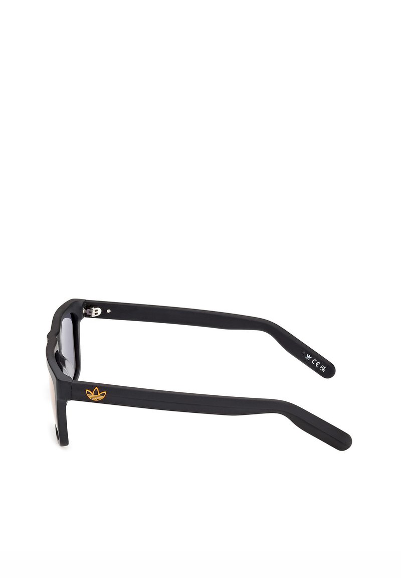 Gafas de sol rectangulares negras con patillas gruesas, que cuentan con un pequeño logo naranja de Adidas en la patilla izquierda y la marca CE en la patilla derecha.
