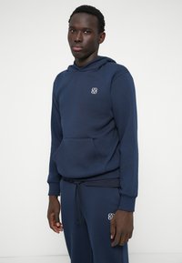 Navy blue hoodie made of soft fabric, featuring a front pocket and a small logo on the chest. Equipped with a drawstring hood.