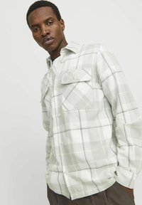 Camisa de cuadros gris claro con botones, con dos bolsillos en el pecho, detalles en blanco y amarillo pálido, y un diseño de ajuste relajado.
