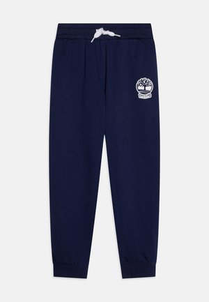 Tengerészeti kék pamut melegítőnadrág, amely rugalmas derékpánttal és zsinórral, valamint bordázott mandzsettákkal rendelkezik. Fehér Timberland logóval van ellátva.