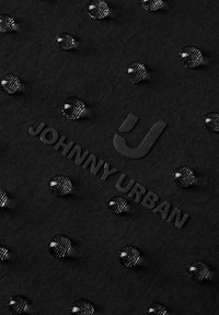 Sort stof med vanddråber, der perler på overfladen, med det fremhævede "Johnny Urban"-logo og det stiliserede "J"-emblem.