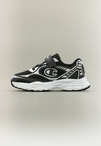 Chaussure de sport noire et blanche avec tige en mesh, col rembourré, sangle ajustable et semelle extérieure en caoutchouc texturée ; logo sur le côté.