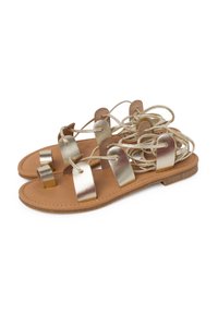 Gold metallic sandals with a flat sole, featuring three wide straps and functional lace-up detailing. Tan leather footbed with minimal accents.